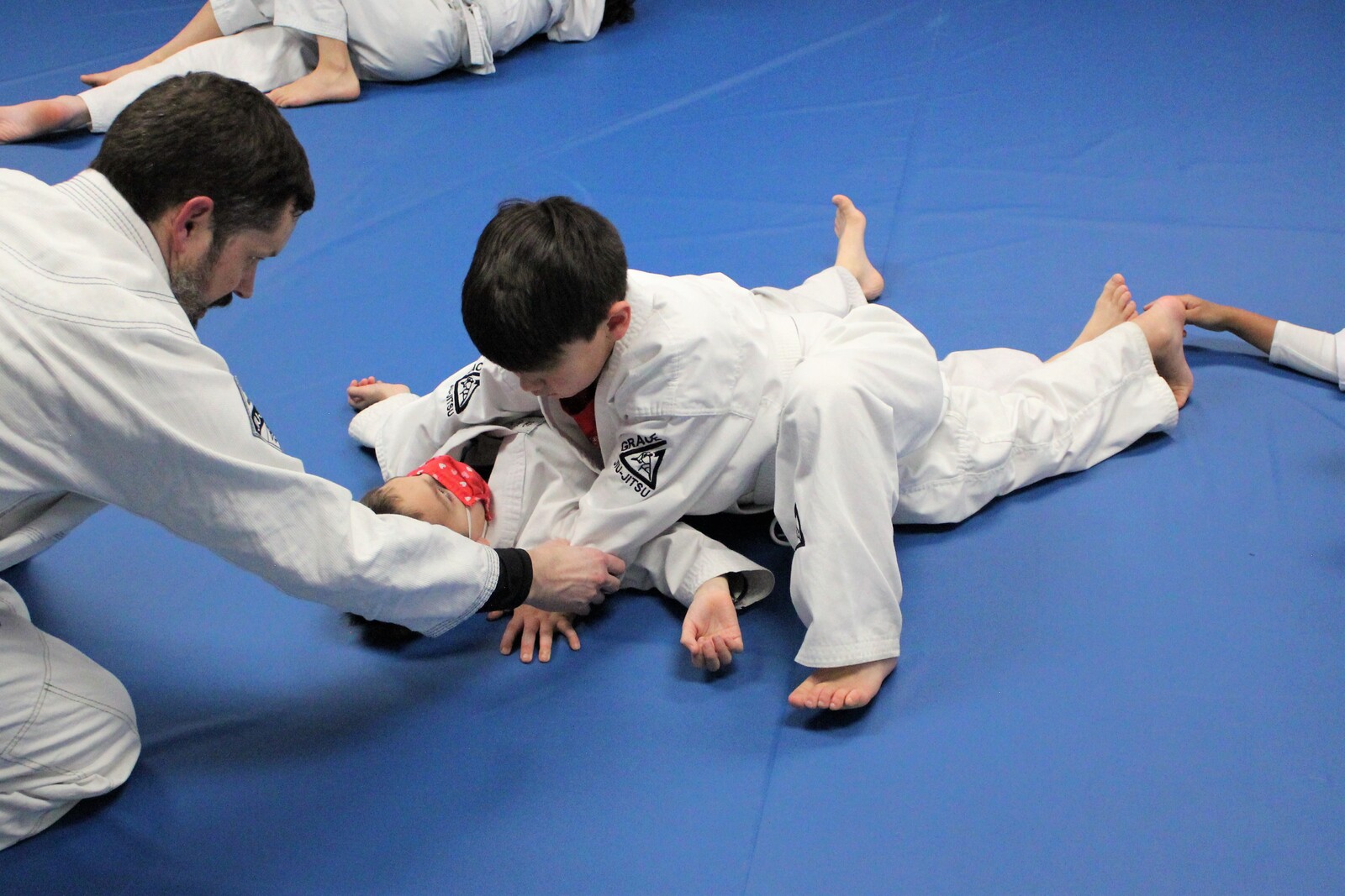 A coach teaching a Youth Jiu-Jitsu student on the mat