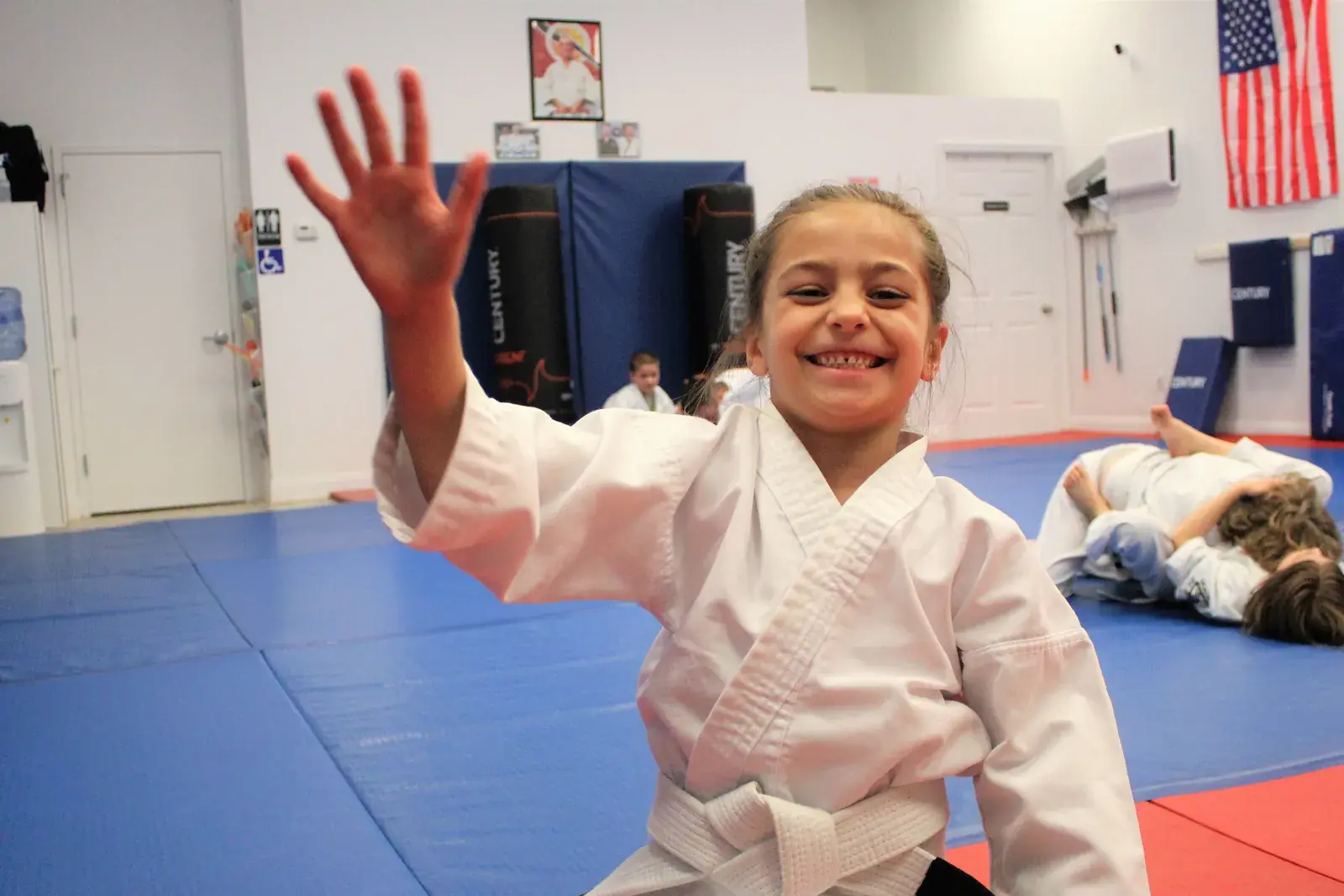 Smiling Little Dragons student waving in class