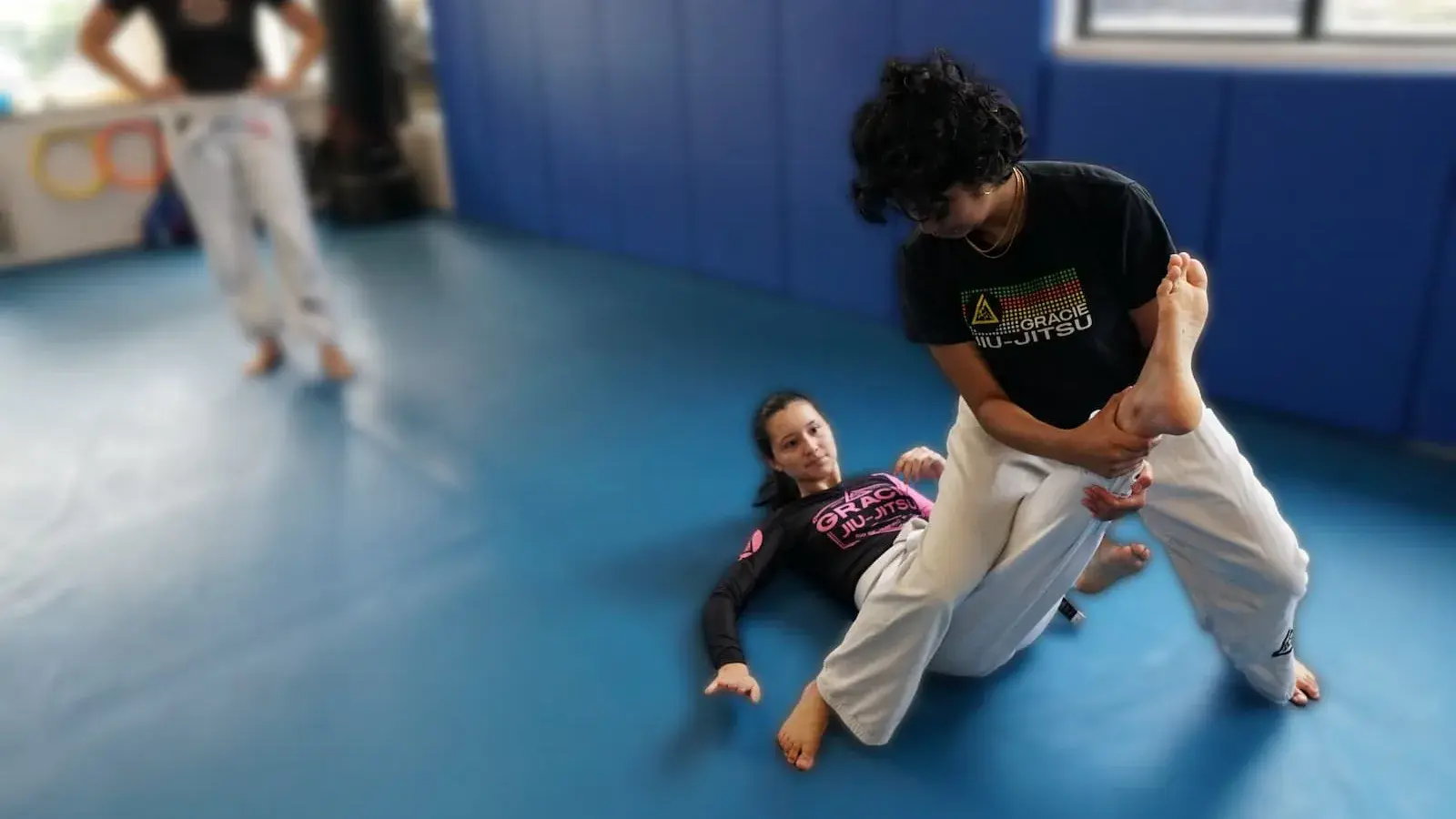 Two women practicing a knee bar in Women's Self-Defense class