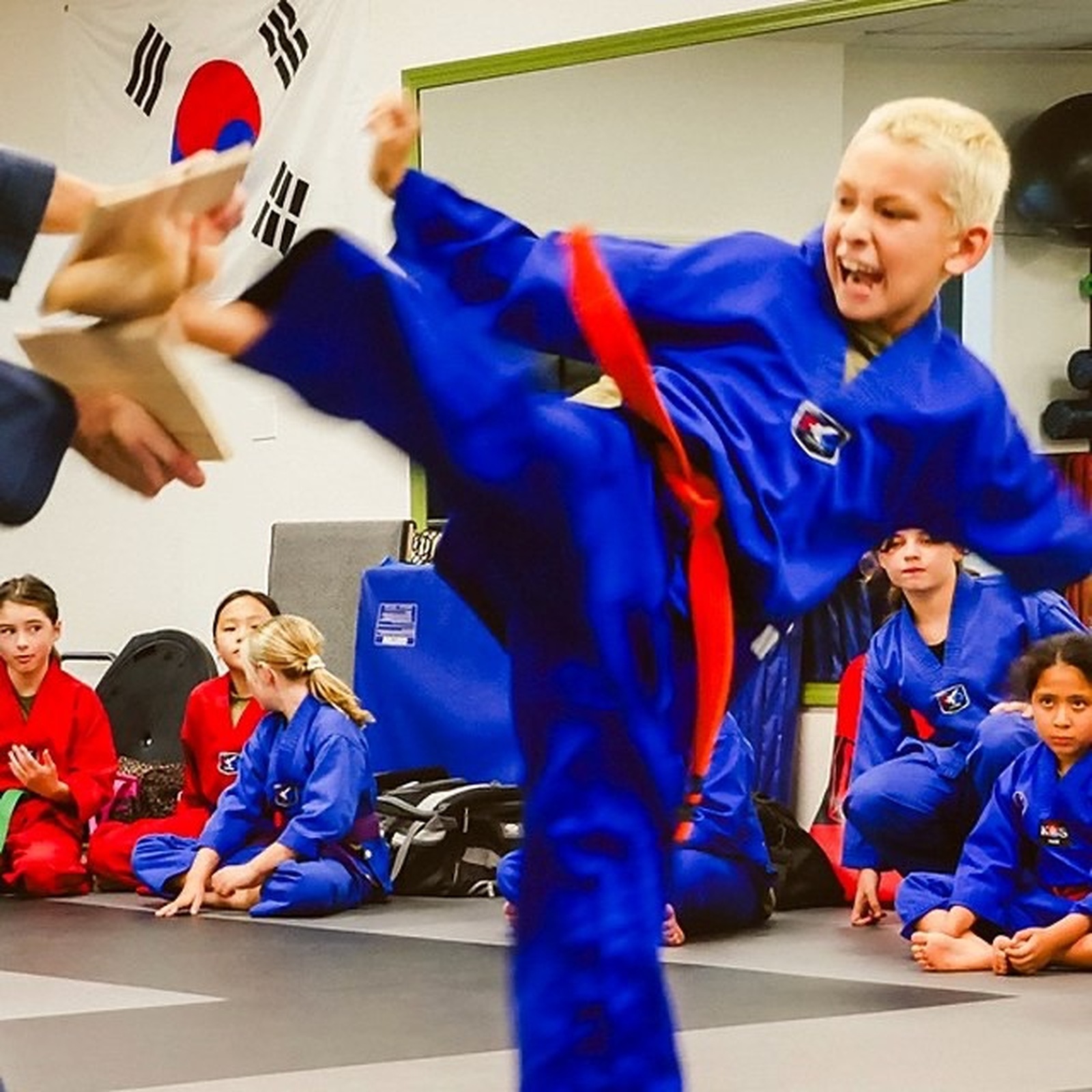 Young student performing a high kick during Taekwondo class