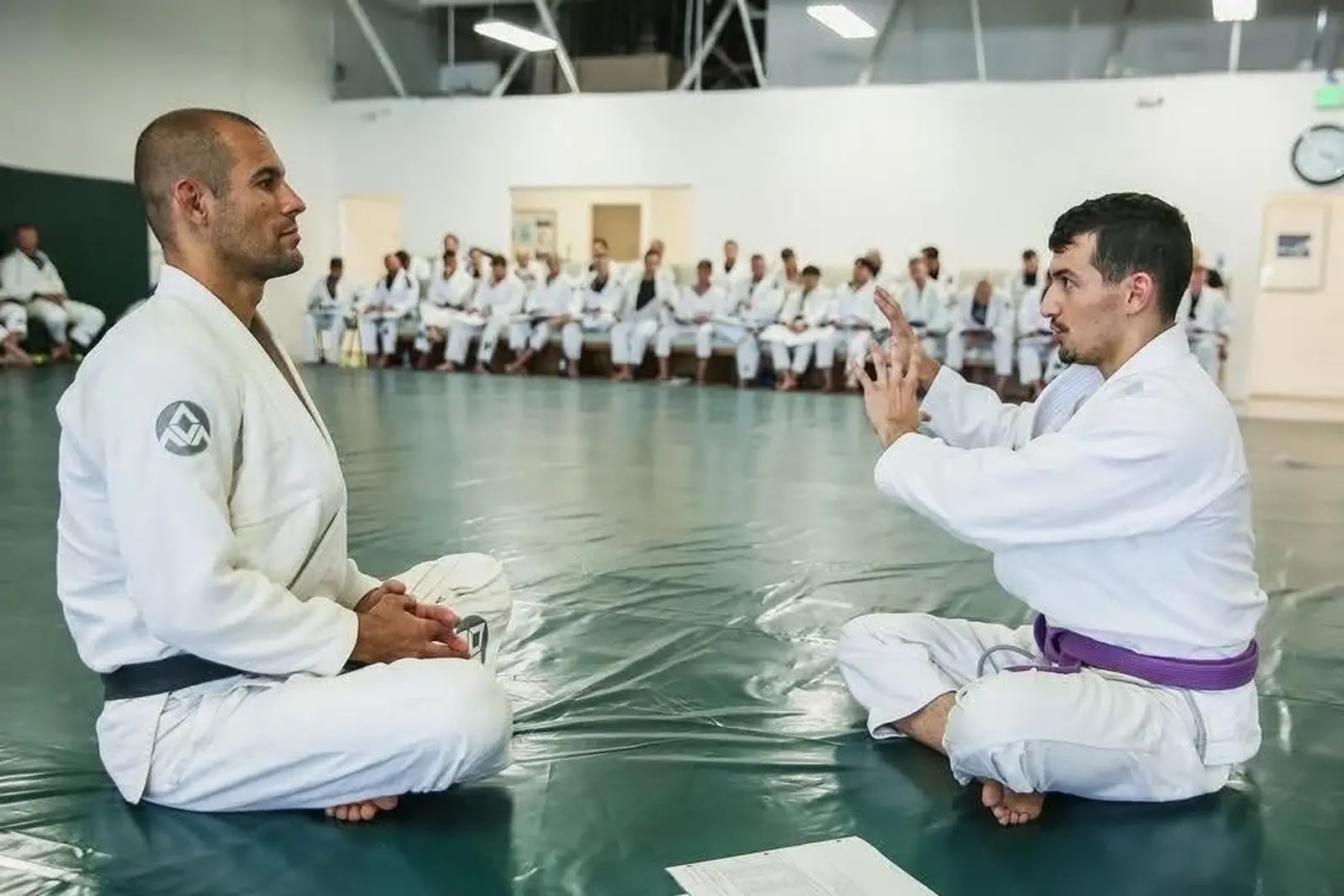 Two adults studying a jiu-jitsu technique in white gis