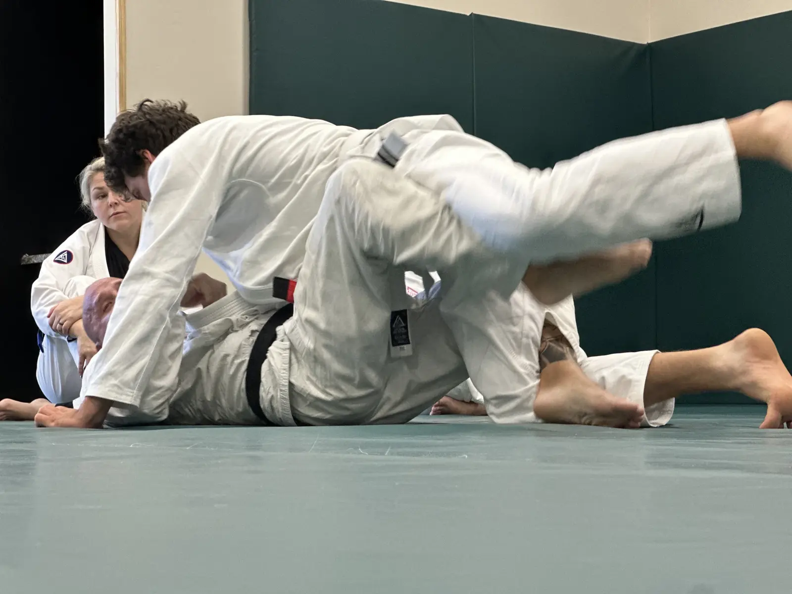 Adults practicing a ground technique in white gis