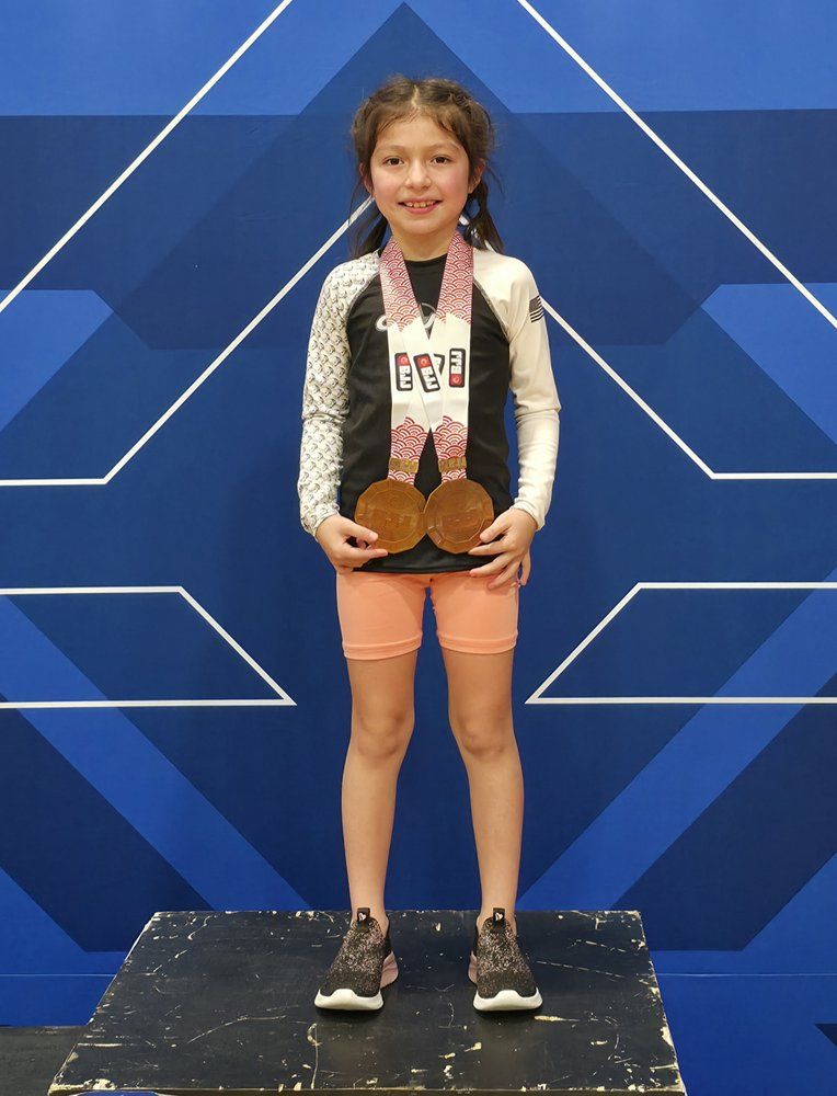 Young CJJF North Carolina student on the podium wearing her tournament medals