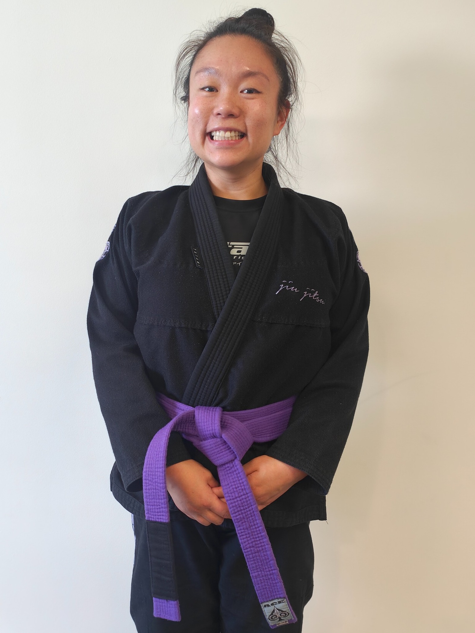 Micah, kids coach and purple belt at Focus Jiu Jitsu, smiling in a black gi