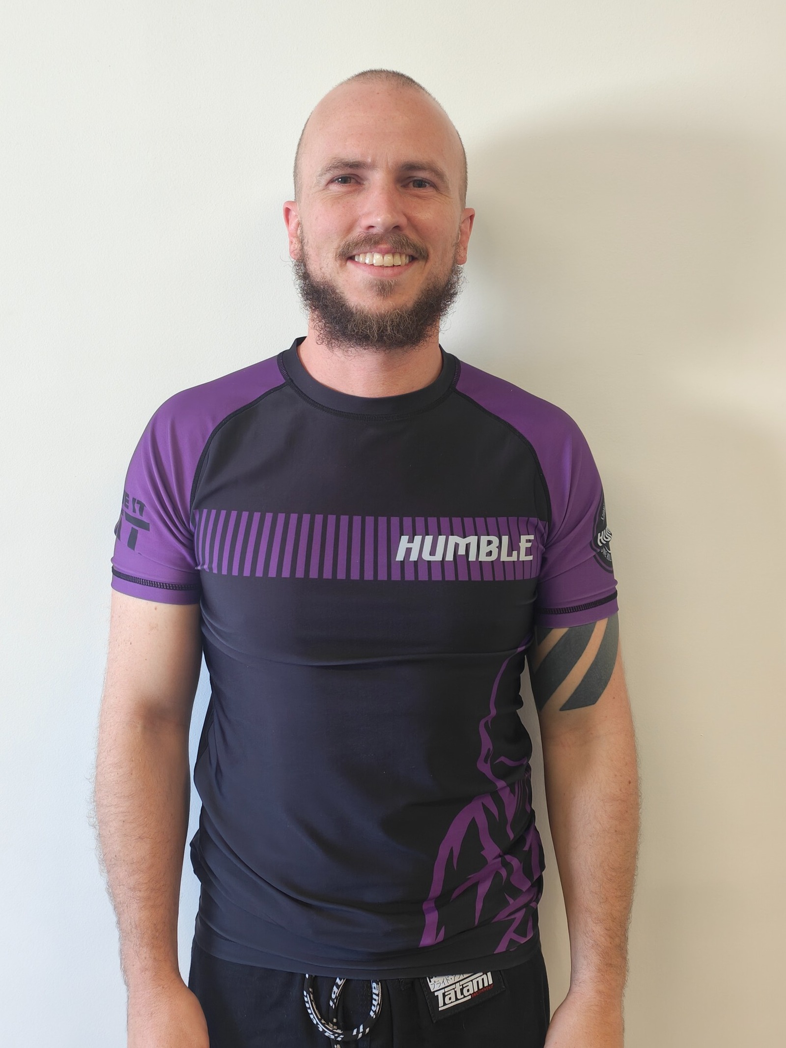 Stuart, No-Gi coach and purple belt at Focus Jiu Jitsu, smiling in a purple rash guard