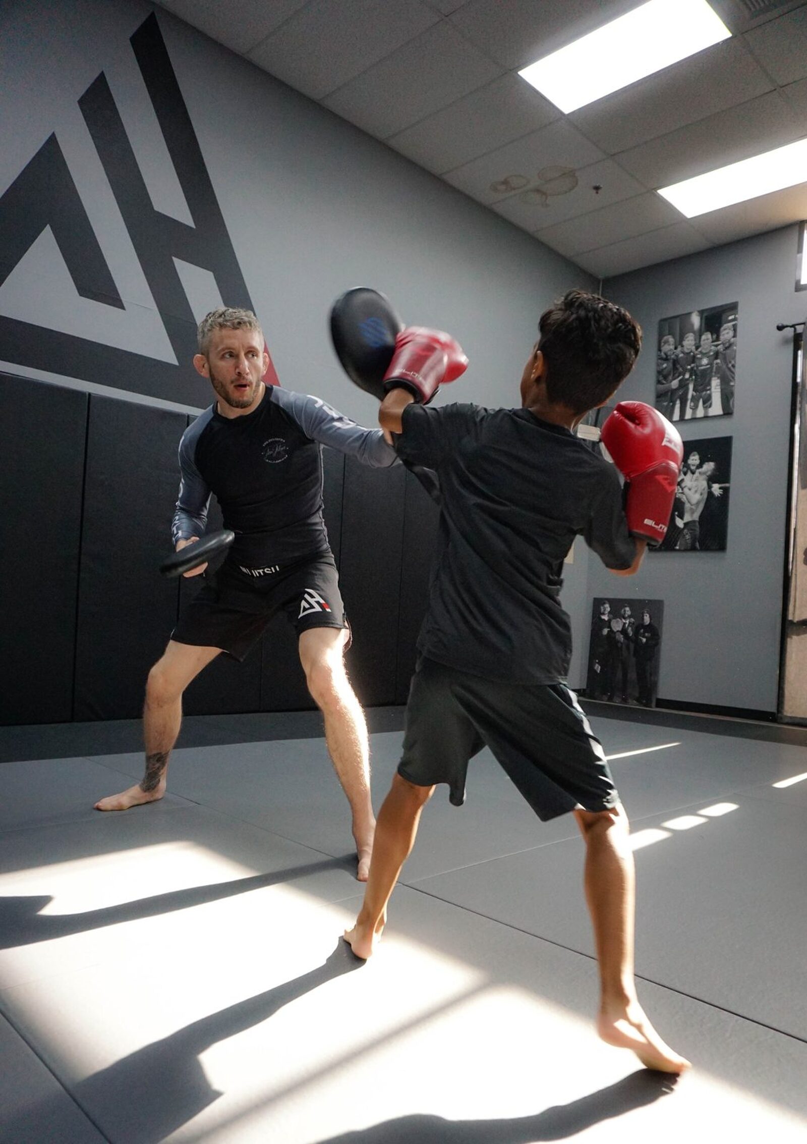 Coach holding focus mitts for a young boxer