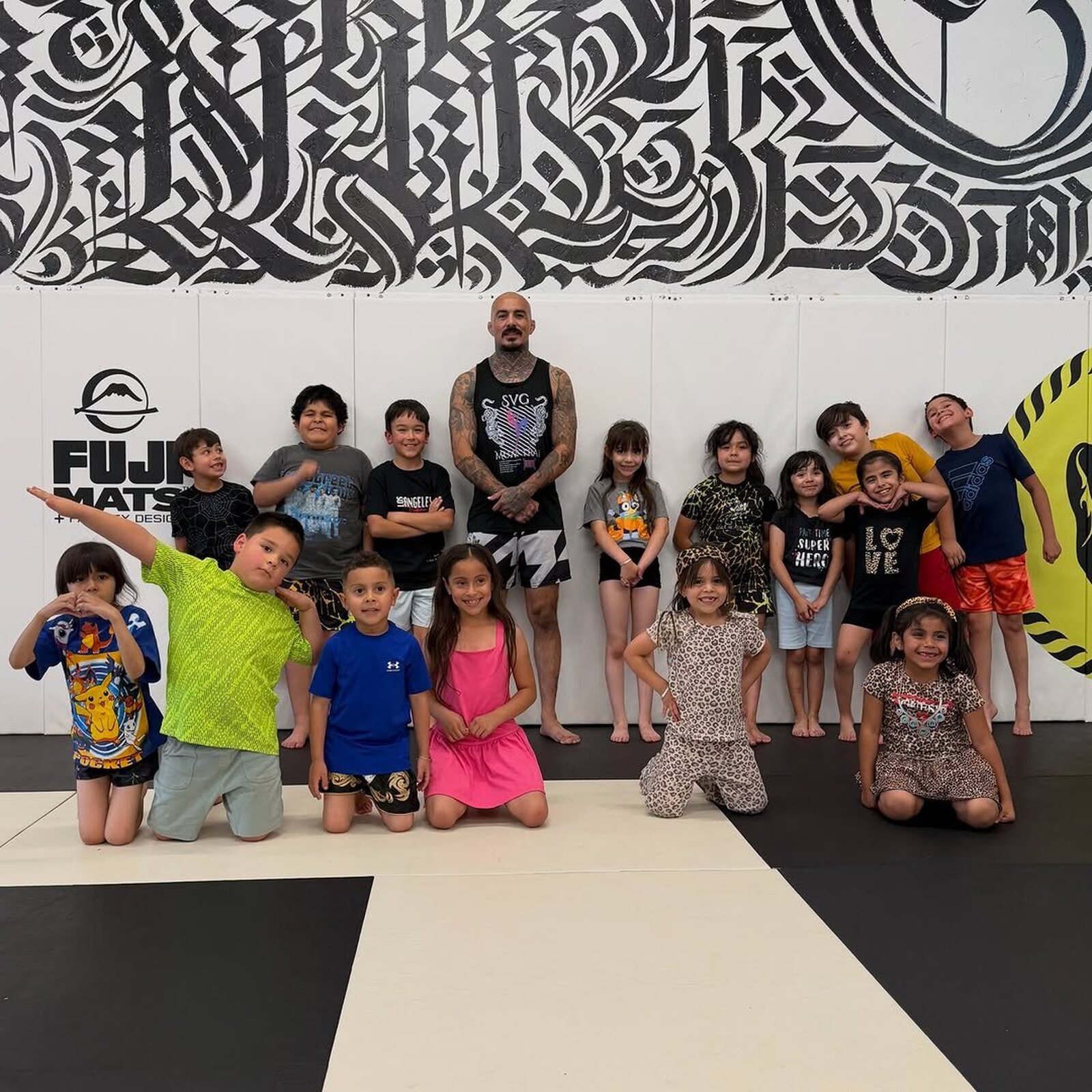SVG kids class lined up on the mats with their coach, smiling and giving thumbs up