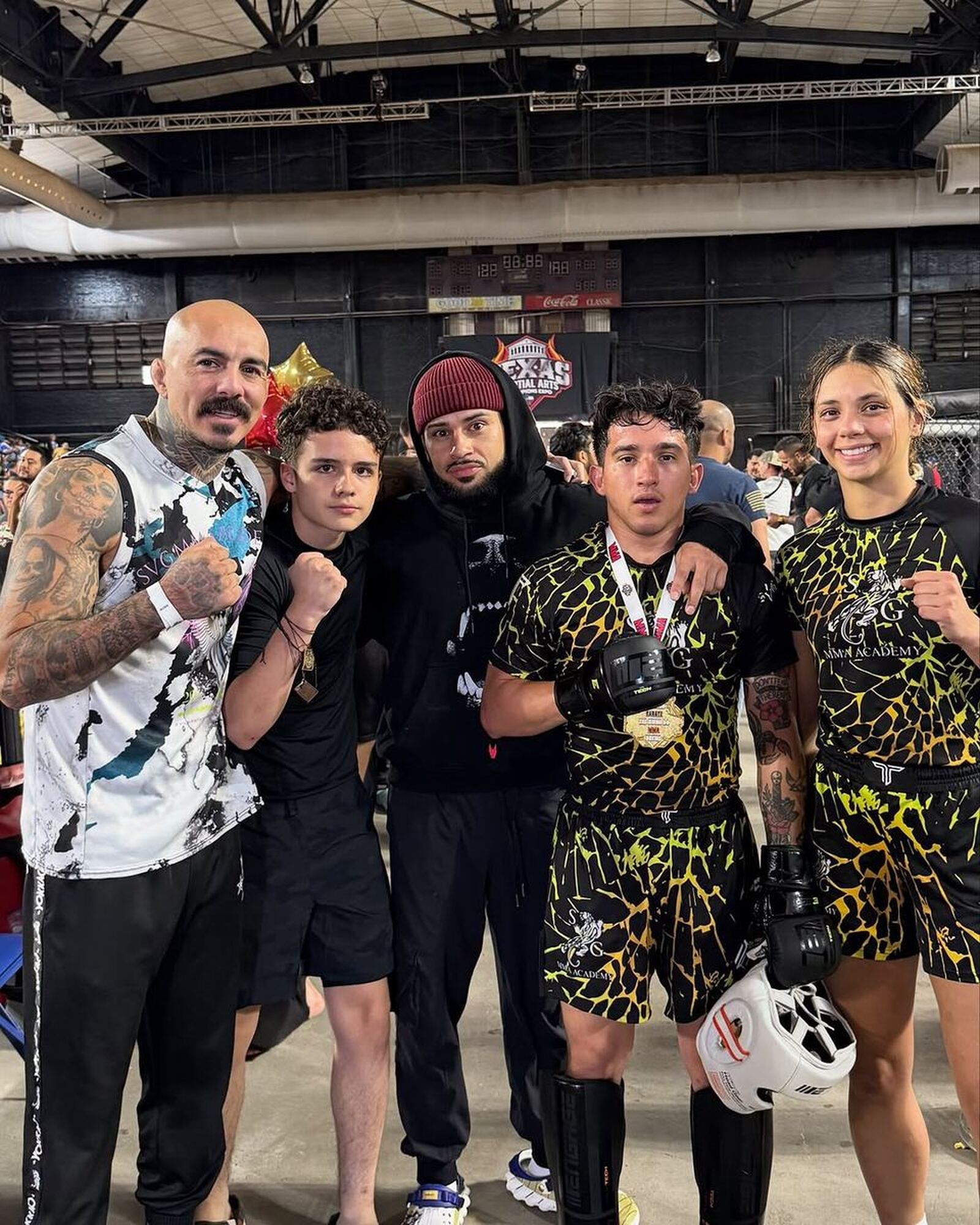 SVG coach and athletes wearing their medals at the Texas Martial Arts Champions Expo, fists raised