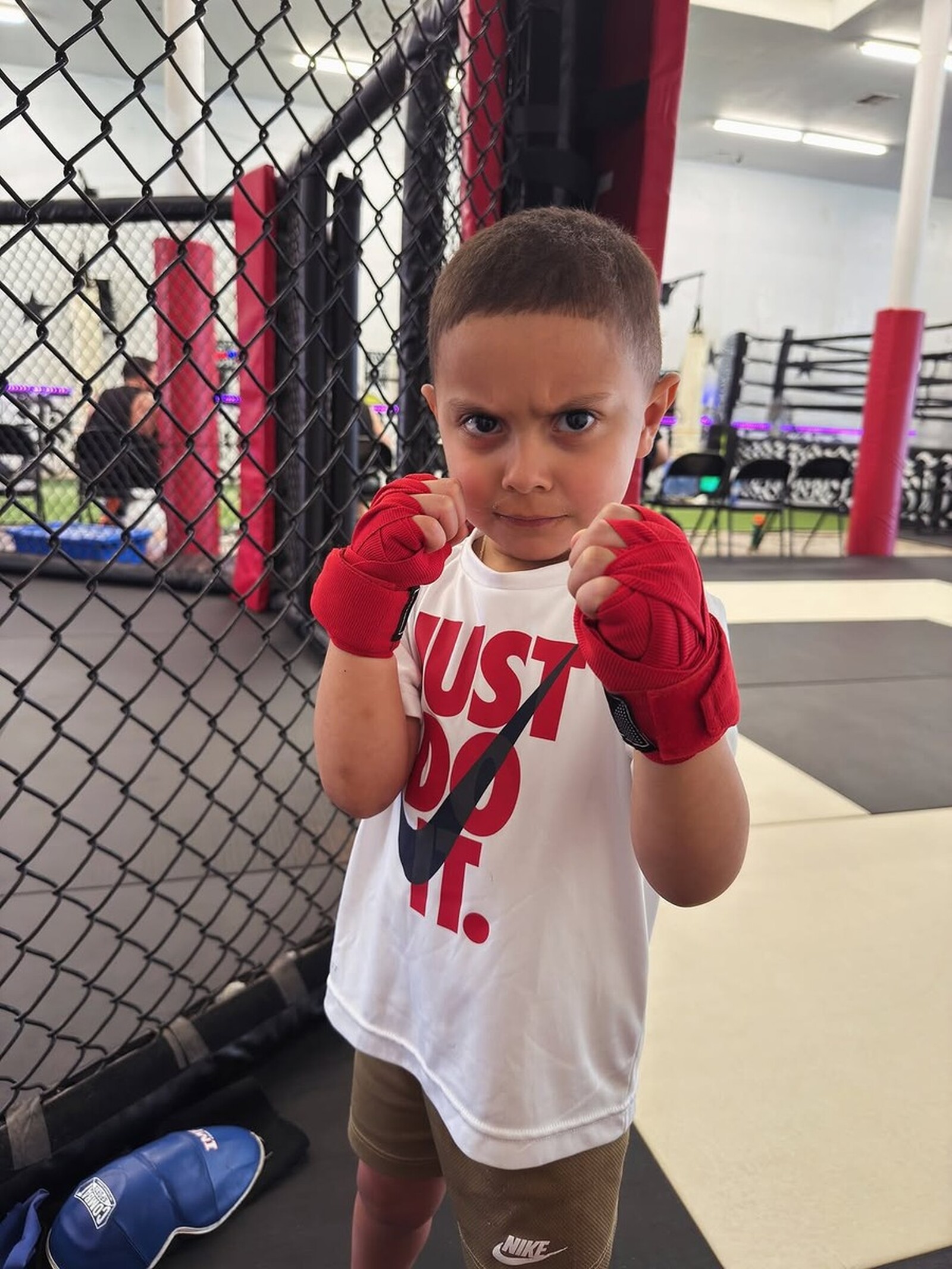 SVG MMA Academy: kids, Little Diego in red gloves staring down the camera in the cage